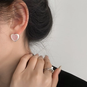 Elegant pink heart earrings and silver cross ring set on a fashion-forward female model