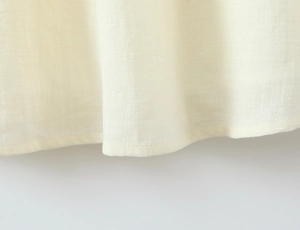 Detailansicht der cremefarbenen Baumwoll-Leinen-Struktur und Saumnaht am Kleid