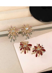 Macro detail of red and pink firework earrings with heart zirconia in golden setting
