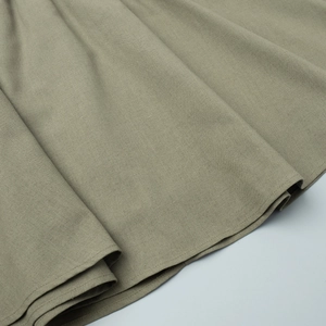 Detailed macro view of grass green cotton linen fabric texture and pleated skirt hemline