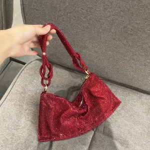 Detailed view of red rhinestone handbag with knotted shoulder straps and gold hardware