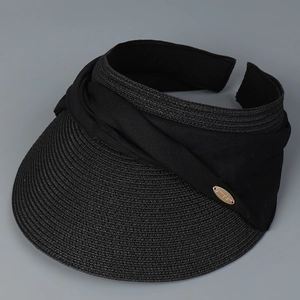 Detail of black woven straw visor with wide brim and elegant metal logo plaque decoration