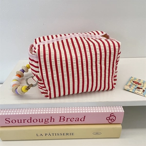 Detail of red and white striped fabric tissue pouch with colorful beaded handle strap
