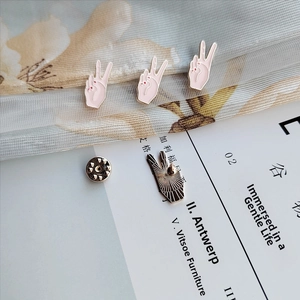 Detailed view of pink enamel peace sign hand pins with golden edges and butterfly clutches