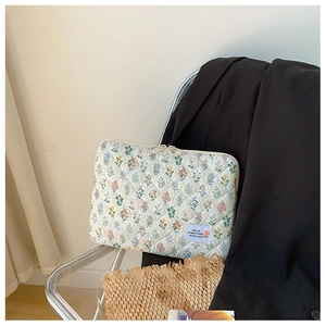 Quilted floral laptop sleeve with 'HELLO' patch detail on a transparent chair