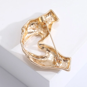 Detailed view of the back pin mechanism and textured gold metal finish of the hand brooch