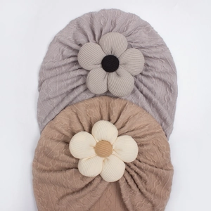 Detail of greyish-purple and khaki baby turban hats with large knitted flower accents