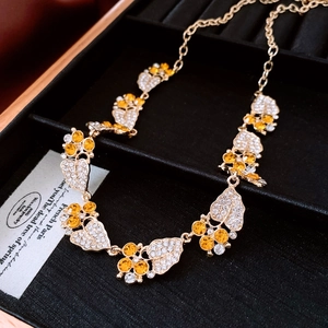Macro shot of vintage leaf-shaped gold pendant necklace with yellow zircon on black velvet