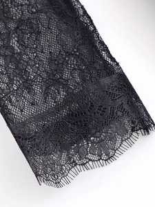 Detailed close-up of intricate black floral lace fabric with delicate eyelash trim edges