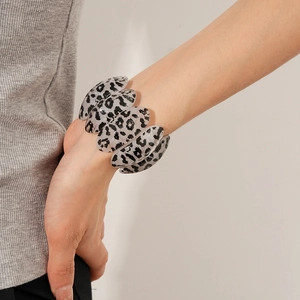 Detailed view of grey leopard print acrylic wide bangle with oval segment design