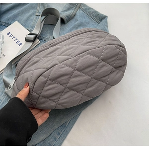Detail view of a grey quilted nylon crossbody bag with adjustable strap and zipper