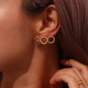Detailed view of gold-layered hoop earrings with green gems and white pearls