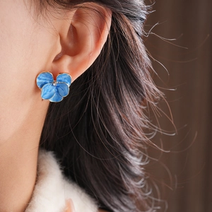 Gros plan sur la boucle d'oreille fleur vintage bleue avec bord doré et cristal