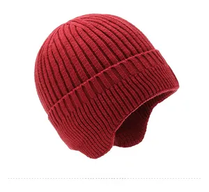 Side view of bright red thick knit beanie showing warm ear flaps and chunky texture