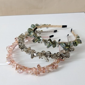 Detailed view of handmade crystal headbands in pink, grey, and olive green colors