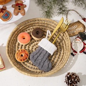 Detailed view of grey knitted Christmas stocking used as cutlery holder with golden utensils