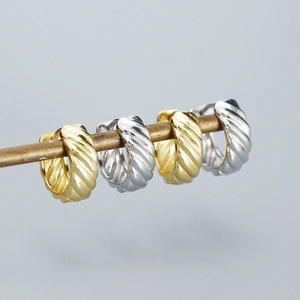 Detailed view of silver and gold croissant hoop earrings with spiral texture on a metal bar