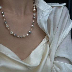 Retro multi-colored lustrous pearl necklace with gold chain on silk shirt model