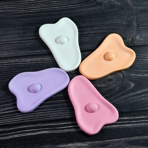 Set van vier gekleurde massage-schrapers in macaron-tinten op een houten achtergrond