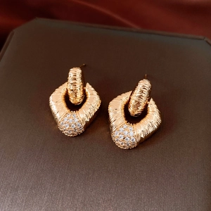 Close-up of gold twist earrings with white crystal pave on a luxury brown silk background