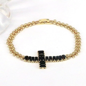 Detailed close-up of a golden chain bracelet featuring a black gemstone cross pendant