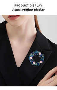 Dettaglio della spilla a ghirlanda con cristalli blu e fiori rosa su abito elegante