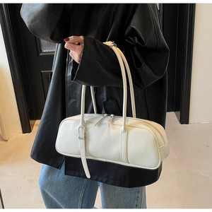Minimalist white baguette bag shown as a sleek shoulder bag held by a model in a leather jacket