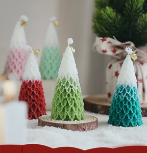 Close-up of snow-capped Christmas tree candles with golden bells on rustic wood