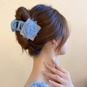 Dettaglio di un fermaglio per capelli con rosa di pizzo blu su uno chignon