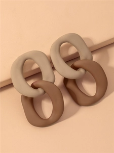 Close-up of matte geometric acrylic link earrings in beige and dark brown color