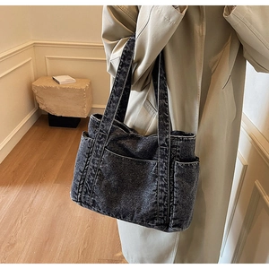 Detail view of large dark grey denim tote bag showing side pocket and washed texture