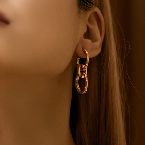 Minimalist C-shaped interlocking double ring gold drop earrings worn by a model
