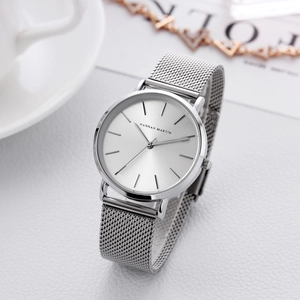 Minimalist silver mesh band quartz watch with 36mm dial on a white textured surface