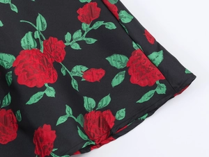 Gros plan sur le tissu floral noir avec roses rouges et feuilles vertes d'une robe