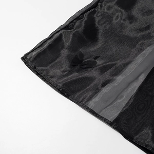 Détail de l'ourlet de jupe en organza noir avec fleurs 3D et texture translucide