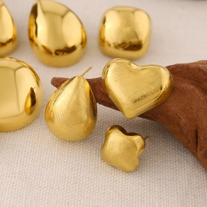 Collection of 18K gold teardrop and clover stud earrings on textured white fabric