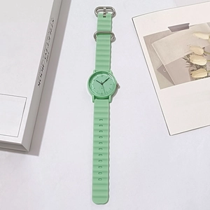 Detailed view of mint green quartz watch with wavy silicone strap on artistic background