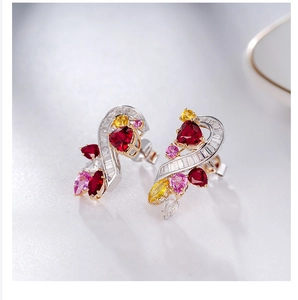 Close-up of heart-shaped ruby earrings with multi-colored gemstones and sparkling pavé diamonds