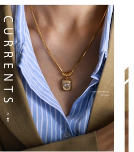 Detail of a vintage layered snake chain necklace with a zircon heart pendant on a model