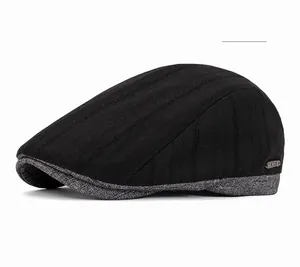 Close-up of black herringbone knit newsboy cap featuring a rectangular side metal logo tag