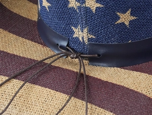 Détail d'un chapeau de cowboy tissé avec motifs d'étoiles bleues et bordure en cuir
