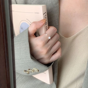 Detailed view of minimalist 925 silver open ring with single white pearl on a model's hand
