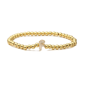 Detailed view of golden beaded stretch bracelet with cubic zirconia letter F charm