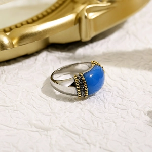 Macro detail of silver vintage ring featuring a blue oval stone and gold beaded trim