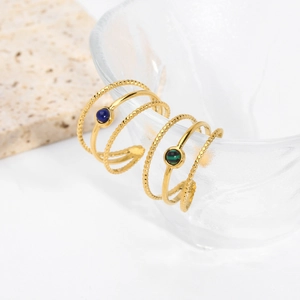 Detailed macro view of 18K gold-plated stainless steel rings with blue and green stones