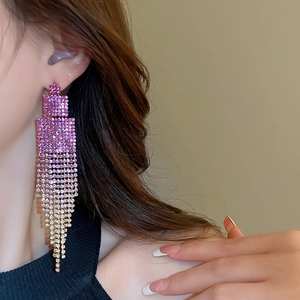 Close-up of long tassel earrings with pink gradient rhinestones worn by a model