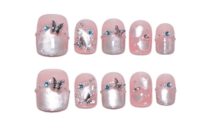 Close-up of pink cat-eye press-on nails with 3D silver butterflies and rhinestones