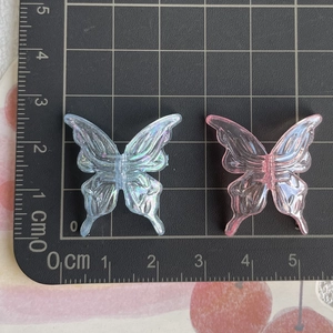 Close-up of pink and blue iridescent acrylic butterfly pendants for DIY phone charms
