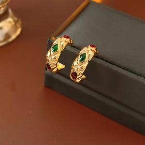 Macro shot of vintage gold C-shape hoop earrings with rhombus pattern and colorful gems