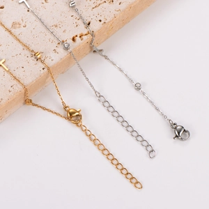 Close-up of gold and silver stainless steel anklets with round stone pendants on stone